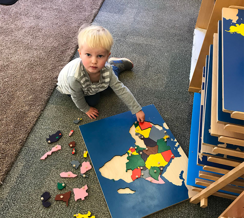 montessori geography student using a map puzzle
